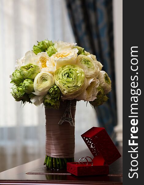 Bouquet of white roses and silver wedding rings.