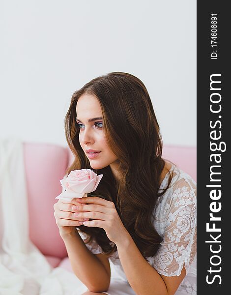 Close-up portrait of young beautiful model with rose at the background of gentle spring colors