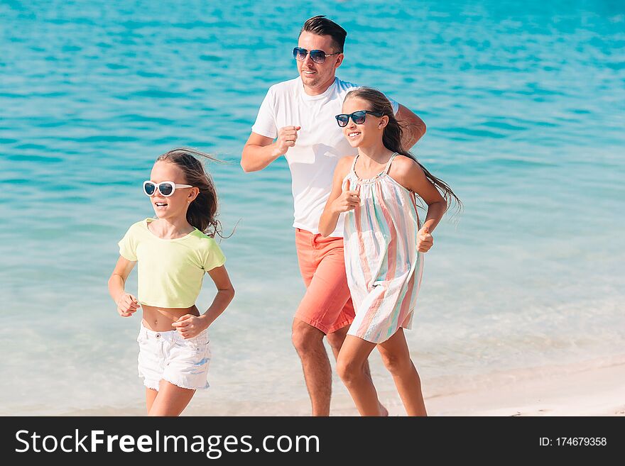 Young family enjoying beach summer vacation. Father playing with kids on the seashore. Young family enjoying beach summer vacation. Father playing with kids on the seashore
