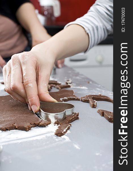 Close up of female hand with heart cookie cutter. Baking brown chocolate cookies. Close up of female hand with heart cookie cutter. Baking brown chocolate cookies.