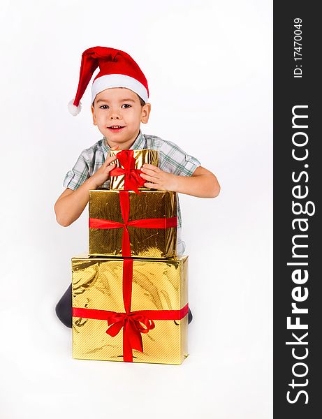 Happy little boy in Santa hat with a bunch of gifts, holiday Christmas, New Year