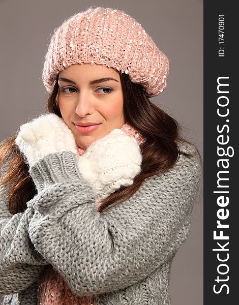 Smiling young girl looks away from camera. Close up of a stunning girl wrapped up warm in winter woollies, including mits, hat, scarf and jumper. Smiling young girl looks away from camera. Close up of a stunning girl wrapped up warm in winter woollies, including mits, hat, scarf and jumper.