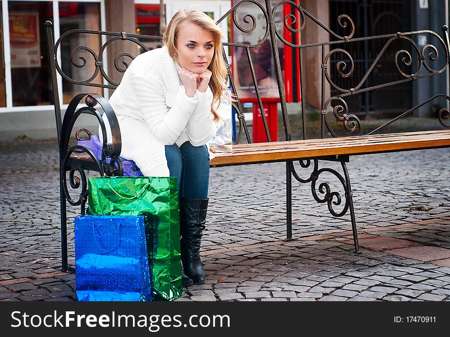 Only young woman sitting on a bench