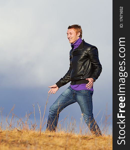 Happy Young Man In The Field Against Clouds