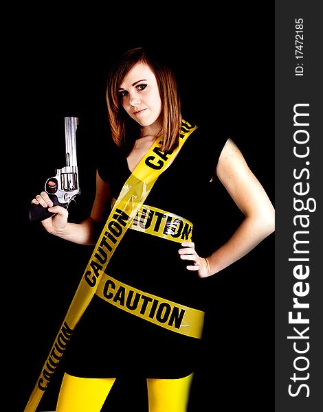 A woman holding a gun on a black background with caution tape wrapped around her. A woman holding a gun on a black background with caution tape wrapped around her.