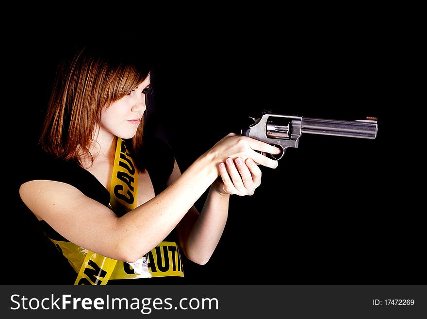 A woman pointing a gun while being wrapped up in caution tape. A woman pointing a gun while being wrapped up in caution tape.