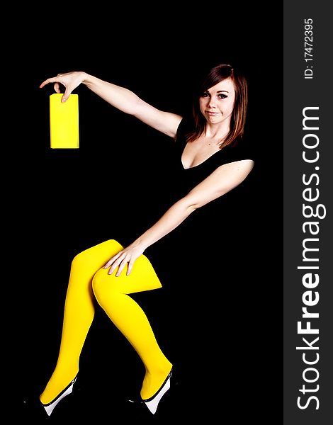 A woman wearing yellow tights in front of a black background wanting to get rid of her boring book. A woman wearing yellow tights in front of a black background wanting to get rid of her boring book.