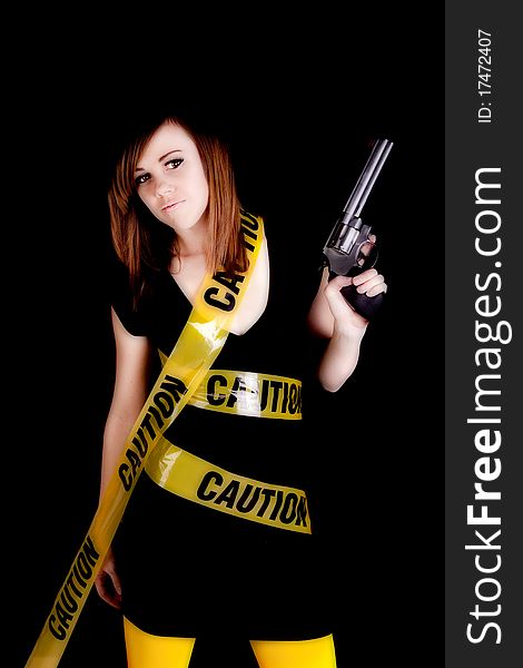 A woman holding a gun on a black background with caution tape wrapped around her. A woman holding a gun on a black background with caution tape wrapped around her.