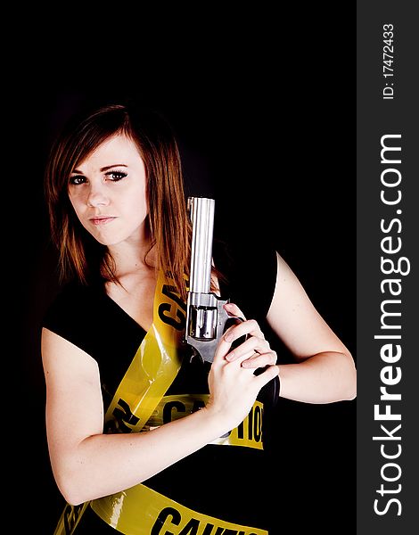 A woman holding a gun on a black background with caution tape wrapped around her. A woman holding a gun on a black background with caution tape wrapped around her.