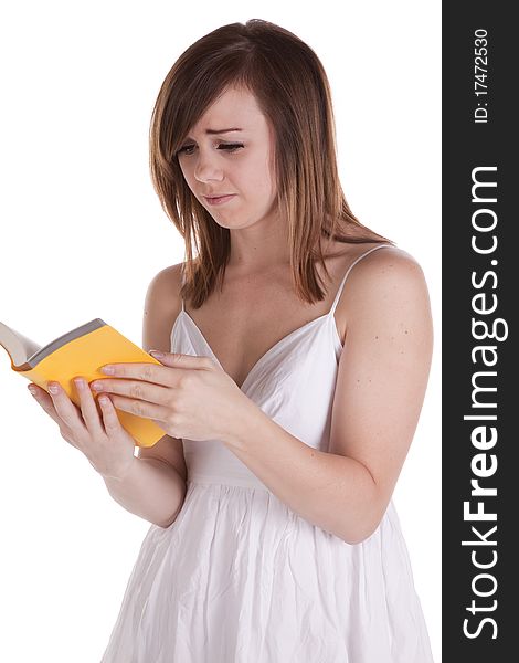A woman with a confused and sad expression on her face reading her yellow book. A woman with a confused and sad expression on her face reading her yellow book.