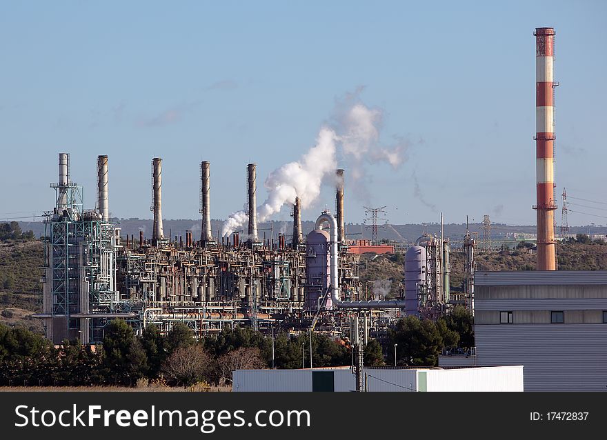 Towers and chimney in oil refinery over blue sky. Towers and chimney in oil refinery over blue sky