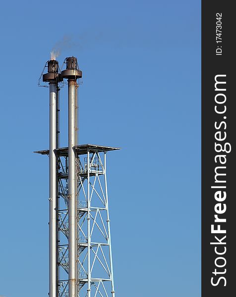 Gas flare of a refinery over blue sky