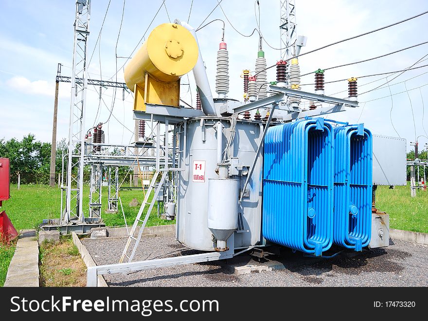 The big electric transformer with wires and insulators against the blue sky