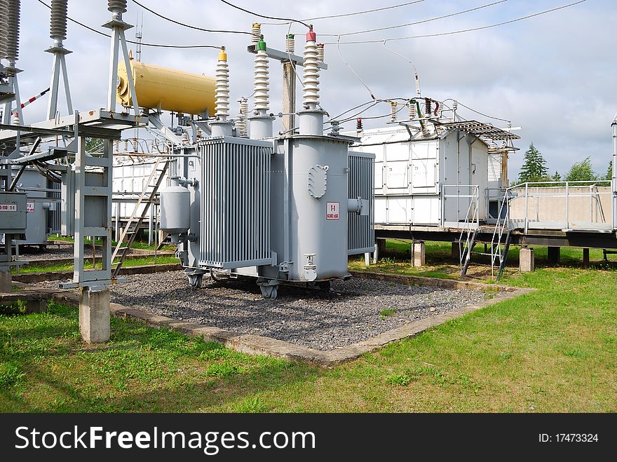 The big electric transformer with wires and insulators against the blue sky. The big electric transformer with wires and insulators against the blue sky