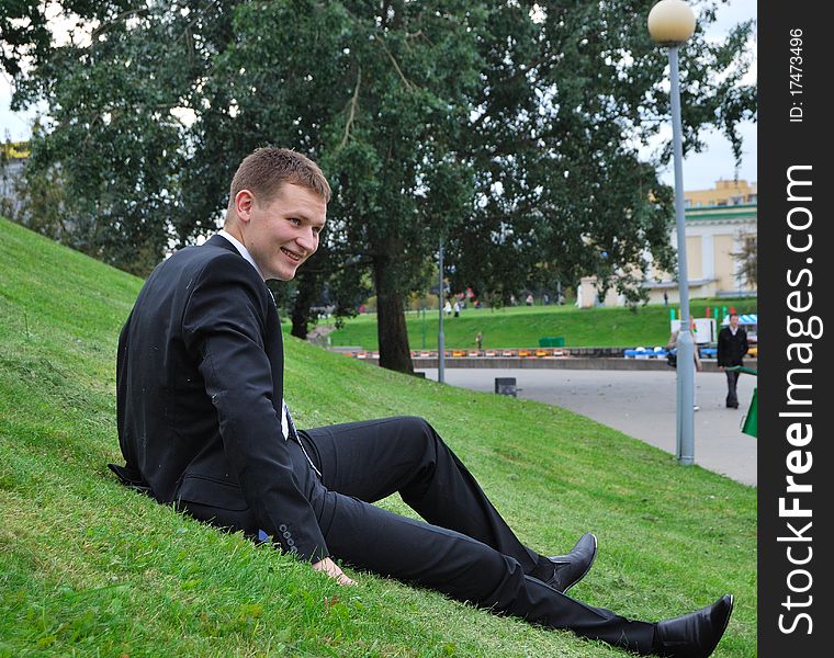 The young guy sits on a grass in a jacket. The young guy sits on a grass in a jacket