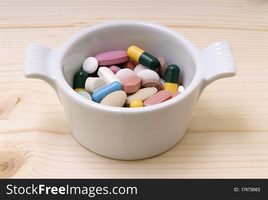 Saucepan with pills on a wooden board