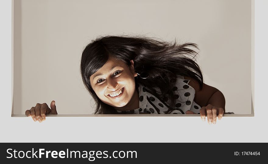 Broad smiling indian lady peeking over a ledge. Broad smiling indian lady peeking over a ledge