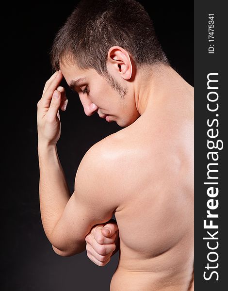 Portrait of the guy, standing a back in studio on a black background. Portrait of the guy, standing a back in studio on a black background.