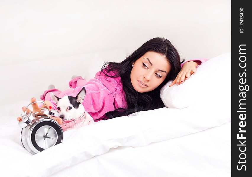 Beautiful young brunette woman with her dog on the bed waking up in the morning. Beautiful young brunette woman with her dog on the bed waking up in the morning