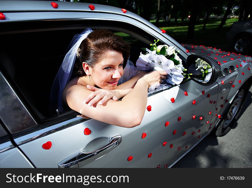 Beautiful bride in a wedding limousine with red little hearts