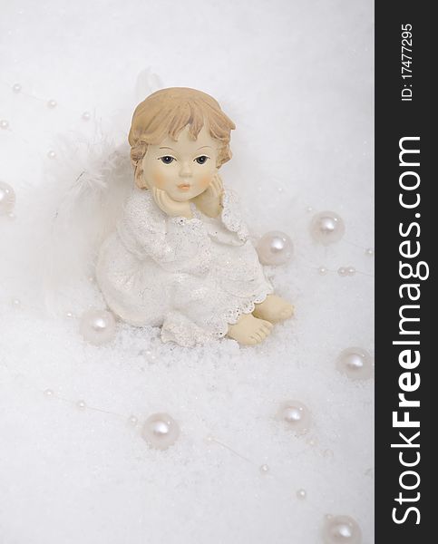 Christmas angel sitting in snow with white pearls. Christmas angel sitting in snow with white pearls