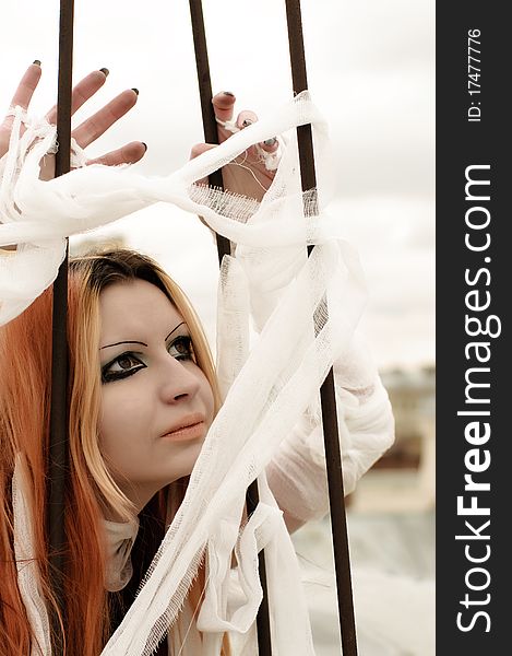 Photo of a Pretty red-haired girl with feathers, bandages and fan on rooftop