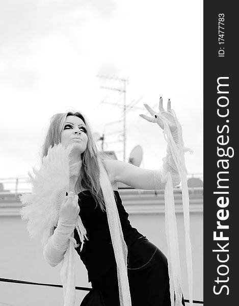 Photo of a Pretty red-haired girl with feathers, bandages and fan on rooftop