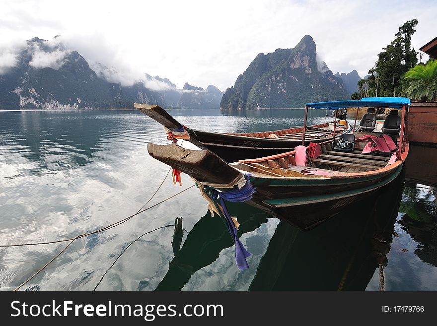 Long tailed boat floating on lake with limestone mountain.