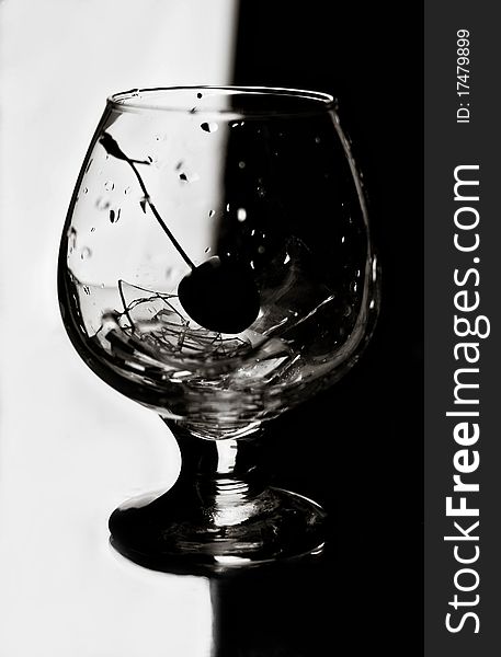 The Black-and-white image of a cherry in a glass with beaten glass