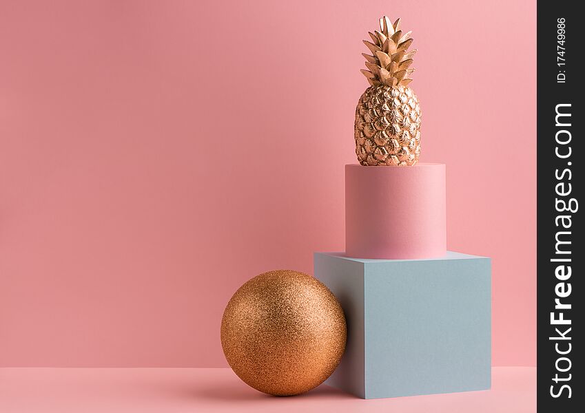 Golden pineapple, glitter ball, teal cube and pink round box on pink background. Minimalistic luxury design. Golden pineapple, glitter ball, teal cube and pink round box on pink background. Minimalistic luxury design.