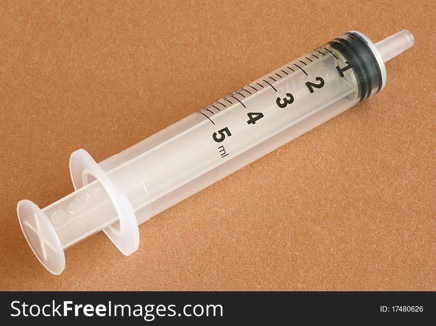 White plastic syringe without needle on brown background