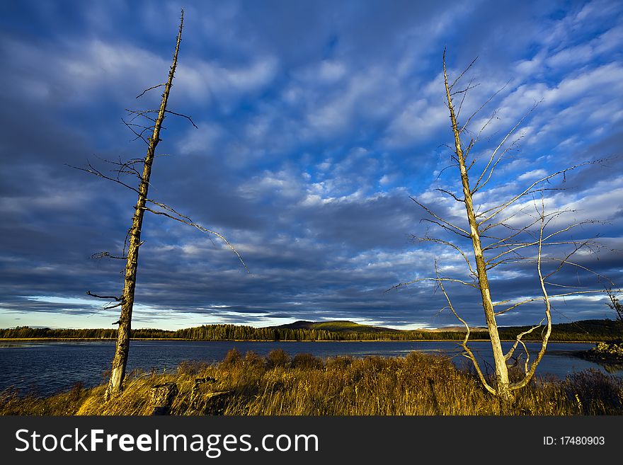 This is a picture of the sunset under the lake and forest.