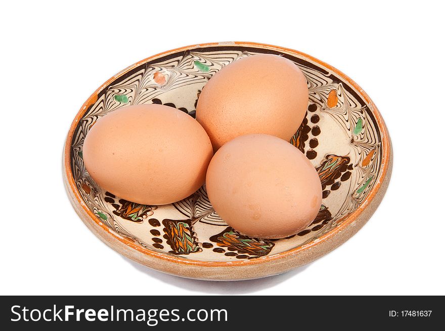 Three chicken eggs on a traditional plate isolated on white. Three chicken eggs on a traditional plate isolated on white