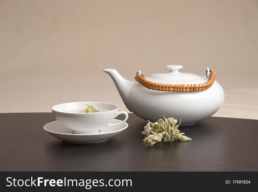 A teapot and a teacup nicely arranged on a table. A teapot and a teacup nicely arranged on a table