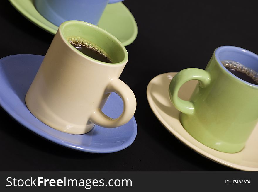 Three cups of espresso in yellow, green and blue cups