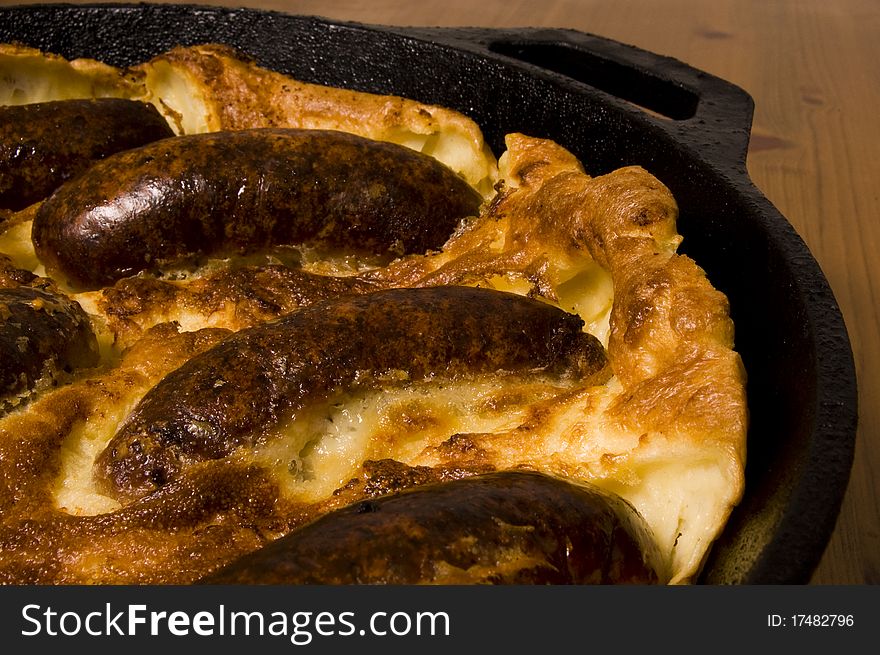 Toad in the hole (British sausage in batter mix) served in iron pan