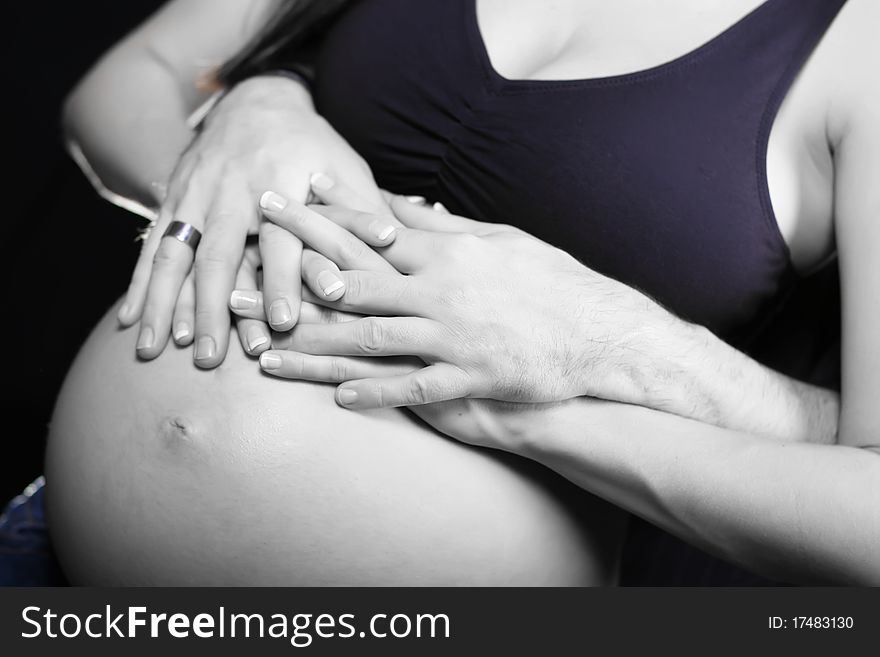 A couple holding hands around a mother's belly. A couple holding hands around a mother's belly