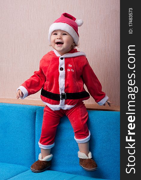 The cheerful kid costs in a suit of Santa Claus. The cheerful kid costs in a suit of Santa Claus