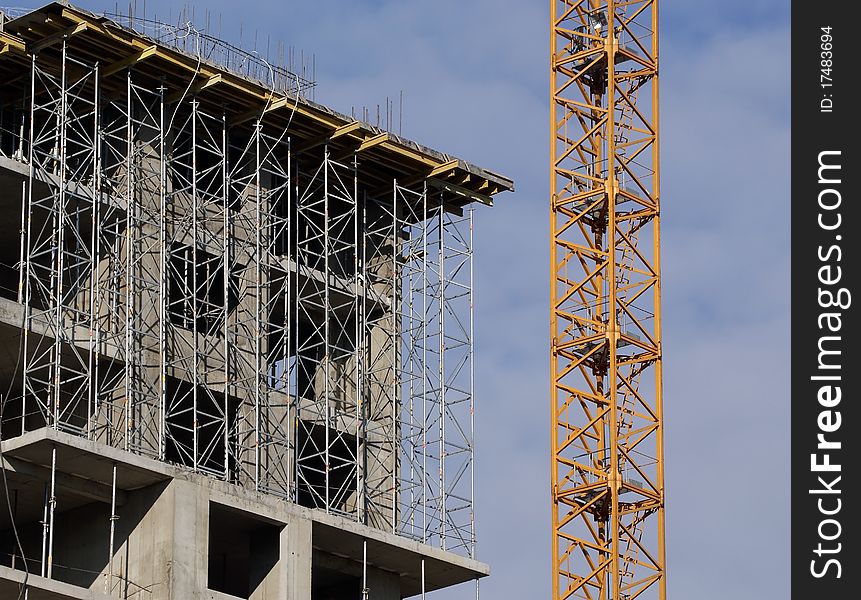 Building crane at the background of a multi-storey building under construction