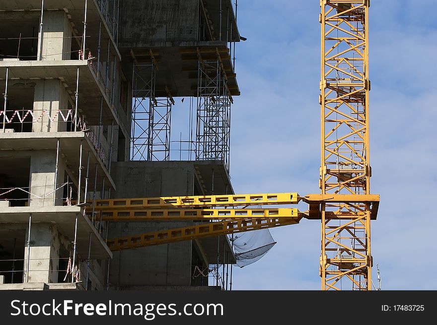 Building crane at the background of a multi-storey building under construction