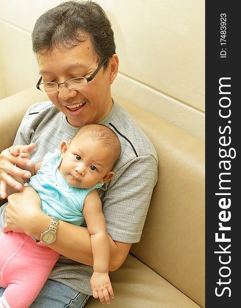 Asian ethnic mature man playing with a baby girl. Asian ethnic mature man playing with a baby girl