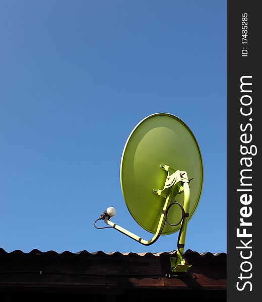 Green satellite dish on the roof with blue sky