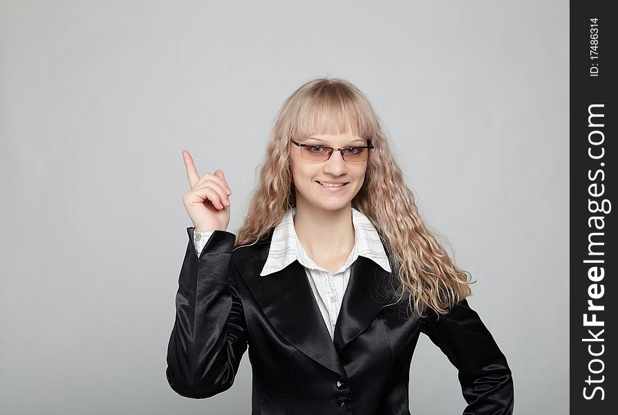 Funny business woman in a black suit with a gray background makes various hand gestures