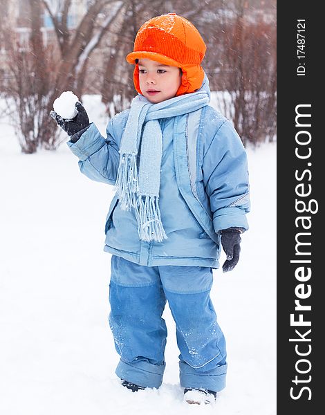 Little boy playing snowballs, snowman sculpts, digs snow. Holidays Christmas and New Year.