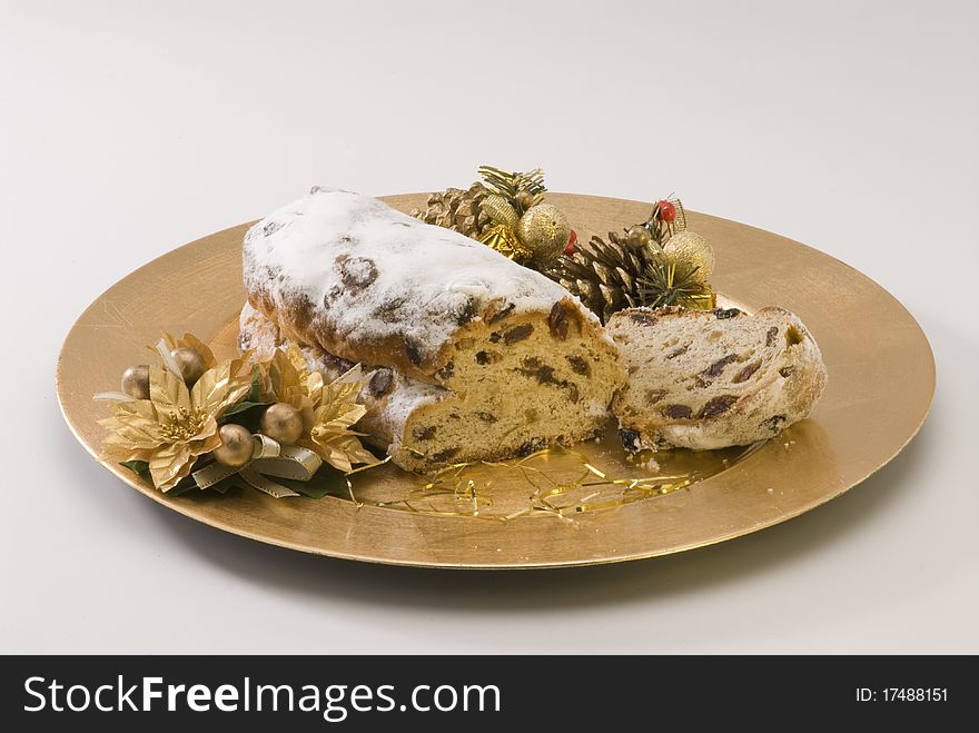 Traditional Christmas stollen filled with raisins served in a golden plate. Traditional Christmas stollen filled with raisins served in a golden plate.