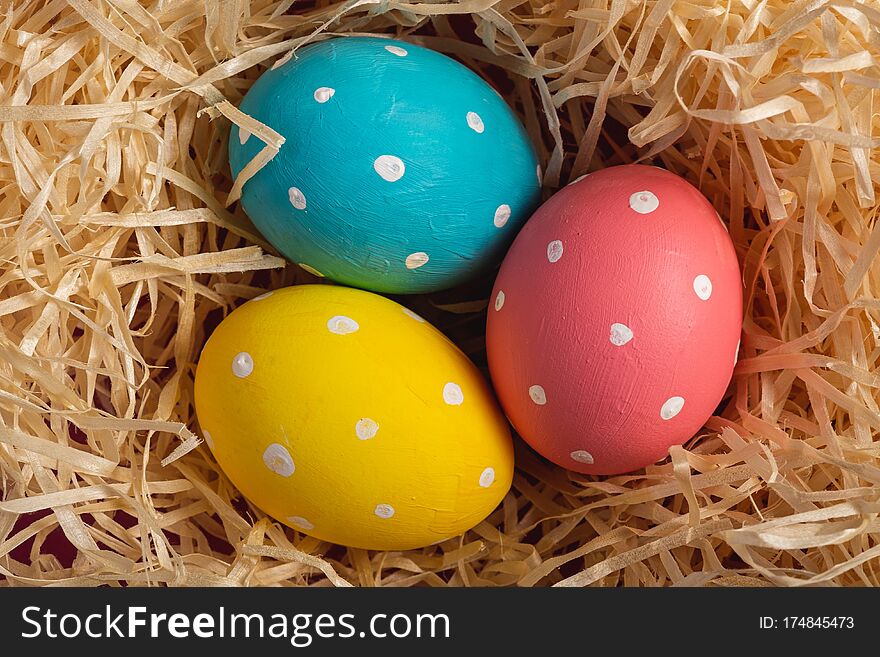 Colorful polka dot Easter eggs in wooden nest, greeting card, top view