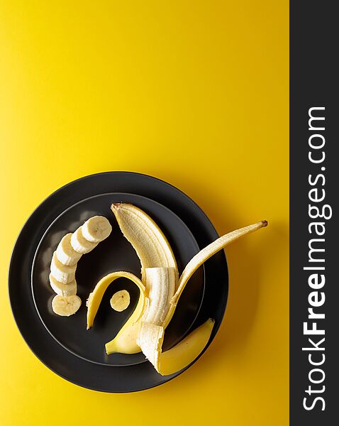 Ripe juicy banana on a black plate. Top view, copy space