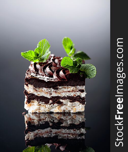 Delicious chocolate cake with mint on a reflective background