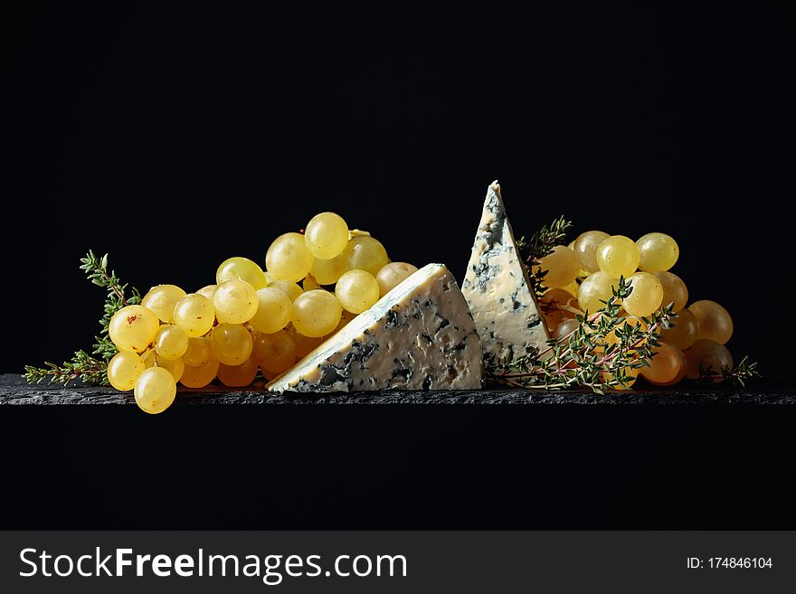 Grapes with blue cheese and thyme on a black background. Copy space