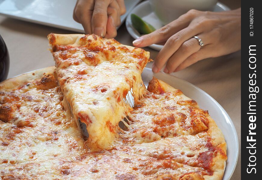 Close up of a woman taking a piece of pizza in a restaurant